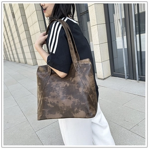 Detailed side view of a large vintage brown tote bag worn on a woman's shoulder outdoors