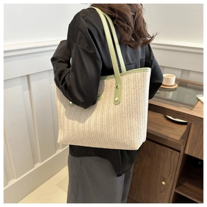 Detail of cream woven tote bag with green leather handles and silver stud accents