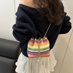 Rainbow hand-woven bucket bag with colorful stripes, gold chain strap, and pearl accents