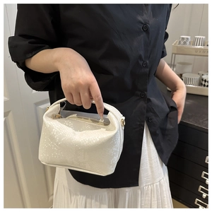 Close-up of white snakeskin crossbody bag with golden hardware and top handle