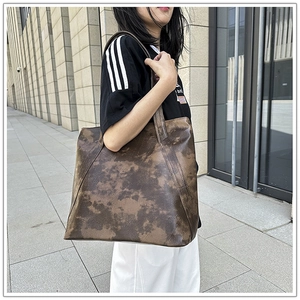 Close-up of a retro brown tie-dye texture tote bag worn on a woman's shoulder
