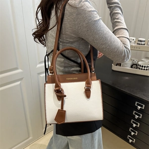 Minimalist white and brown contrast leather crossbody bag shown in a cozy indoor scene