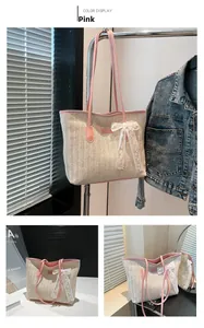 Détail d'un sac cabas en paille avec bordure en cuir rose et nœud en dentelle blanche