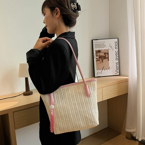 Straw tote bag with pink trim and tassel fringe shown in a lifestyle setting
