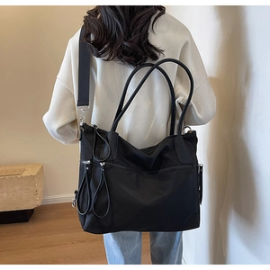 Detail einer schwarzen Nylon-Tasche mit mehreren Reißverschlusstaschen am Modell zur Ansicht