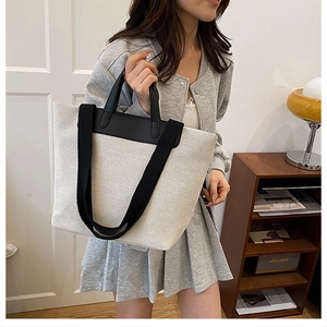 Detail of minimalist cream canvas tote bag with black faux leather straps and trim