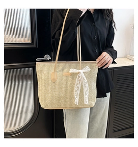 Détail macro du sac cabas en paille beige avec texture tissée et nœud en dentelle