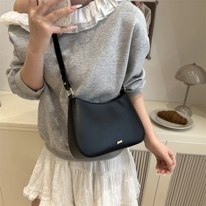 Minimalist black crescent shoulder bag with adjustable strap and golden logo detail