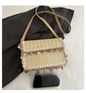 Detailed straw woven square bag with delicate lace trim and natural sea shell charms
