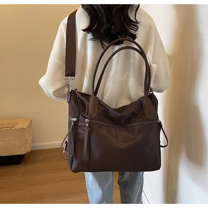 Detail der großen braunen Nylontasche mit mehreren Fächern und Lederakzenten für Damen