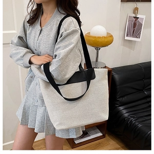 Detail of minimalist cream canvas tote bag with black shoulder straps and leather accents