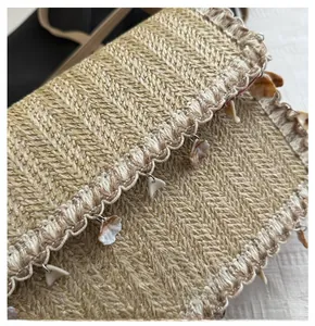 Detailed view of woven straw bag with shell pendants and wave-pattern trim details
