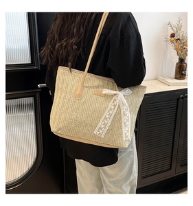 Détail du sac cabas en paille avec nœud en dentelle blanche et anses en cuir