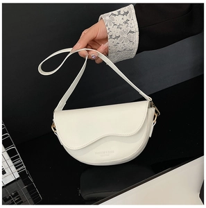 Detailed view of white leather saddle bag with gold hardware and fine stitching