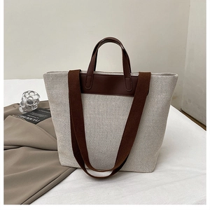 Detail of linen tote bag with brown leather trim and wide canvas shoulder strap