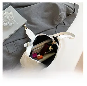 Top view of white leather baguette bag showing spacious interior with phone and cosmetics