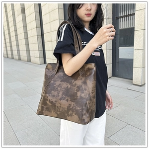 Detailed close-up of a large vintage brown leather tote bag worn on shoulder