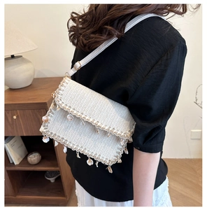 Detail of cream straw woven crossbody bag with real shell charms and leather strap