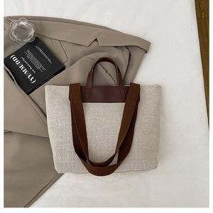 Detail view of large linen tote bag with brown leather handles and wide shoulder strap