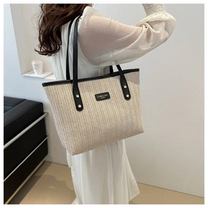 Close-up of V-shaped straw weave texture and black leather strap on tote bag
