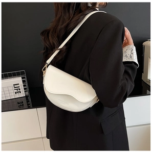 Detail of white saddle bag showing leather texture and wavy flap with golden hardware