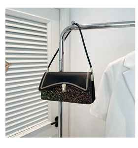 Detail of color-block handbag with sequins and white V-stitch trim on black flap