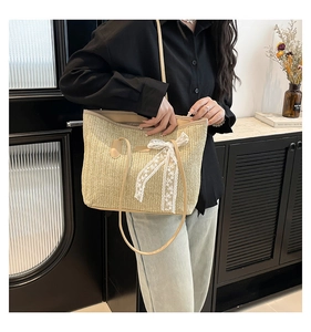 Détail du sac en paille avec nœud en dentelle et bandoulière en cuir de qualité