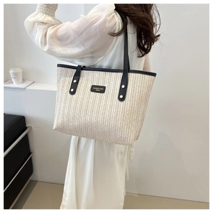 Detail of herringbone woven fabric tote bag with black leather straps and brand plate