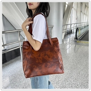 Brown oil-wax leather tote bag with vintage texture shown on shoulder of a female model