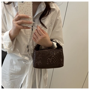 Detail of dark brown snake-patterned leather handbag with metal zipper and top handle