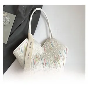 Detail of white textured tote bag featuring wavy colorful embroidery and fashion strap