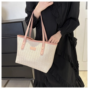 Detail of woven straw tote bag with pink leather trim and metallic rivets