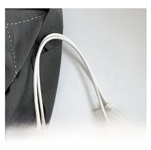 Detail shot of white tote bag featuring colorful embroidery and woven ribbon handle