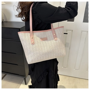 Detail of herringbone woven tote bag with pink leather handles and gold rivet accents