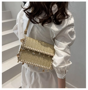 Close-up of woven straw bag featuring delicate lace trim and natural shell charm detailing