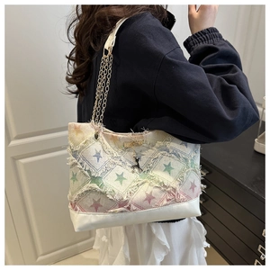 Detail of colorful star pattern denim tote with fringed edges and chain strap