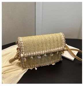 Detail of straw woven texture with shell charms and fringe on a summer crossbody bag