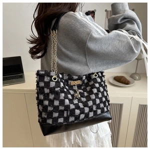 Detail of checkered tote bag featuring a gold chain strap and cute deer charm accessory