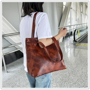 Brown vintage textured leather tote bag shown on model in a modern urban station