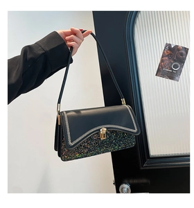 Detail of contrast stitching on black leather bag with glitter panel and gold lock