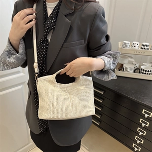 Sac fourre-tout chic en paille tressée beige avec bandoulière porté par un mannequin