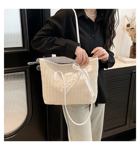 Détail du sac cabas en paille avec nœud en dentelle blanche et fines bretelles élégantes