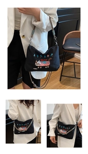 Detail of black canvas crossbody bag featuring cat embroidery and woven handle strap