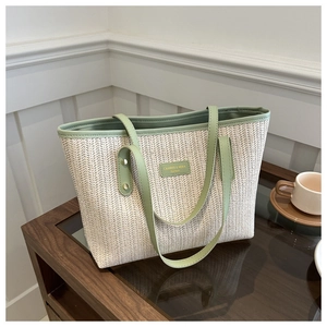 Detail of herringbone straw weave and light green leather handles on the tote bag