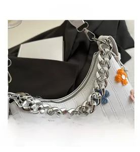 Macro shot of white croc-embossed baguette bag with colorful plush flower patches
