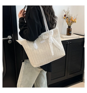 Vue détaillée du sac cabas tissé avec un grand nœud en dentelle et des anses en cuir blanc