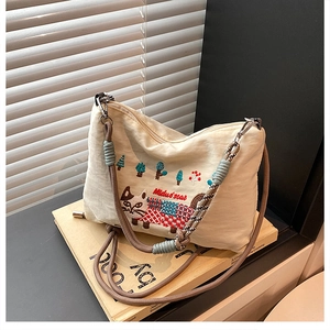 Detailed embroidery of a cat and colorful trees on a heavy beige canvas tote bag