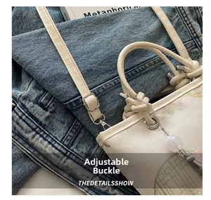 Detail of adjustable metal buckle and embroidery on the white retro Chinese bucket bag