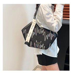 Detail of black quilted tote bag with colorful zigzag stitching and wide woven strap