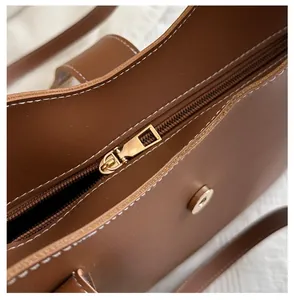 Detail der karamellfarbenen Beuteltasche mit Gold-Reißverschluss und weißen Kontrastnähten